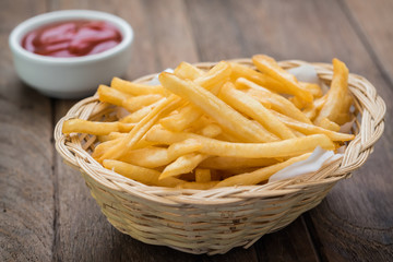 French fries in basket and ketchup on wooden table