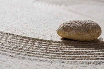 Fototapeta na wymiar zen sand still-life - textured pebble on sinuous waves for concept of wellbeing or beauty spa with inner peace, closeup