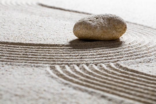 zen sand still-life -single stone on sinuous waves for concept of beauty spa or spirituality with inner peace
