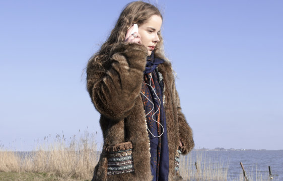 Jonge vrouw staat te bellen met mobiele telefoon aan rand van meer