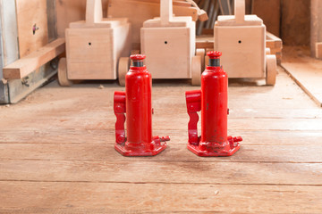 two red hydraulic  car jack on wooden