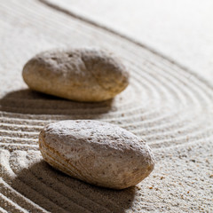 Fototapeta na wymiar zen sand still-life - stones set on sinuous lines for concept of progression or change with inner peace, closeup