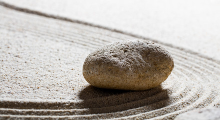 Fototapeta na wymiar zen sand still-life - single stone for the concept of harmony or wellness with care and smoothness, closeup