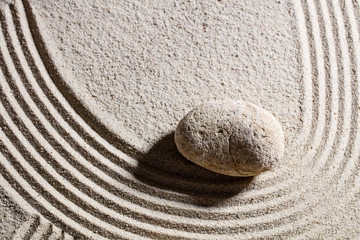 Fototapeta na wymiar zen sand still-life - one stone designing waves or a curve for concept of change or suppleness, top view