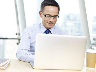 Office worker sitting at desk using laptop computer and smiling