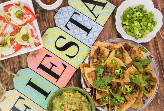 Mexican fiesta table with nachos, tortilla chips, quesadillas, guacamole.