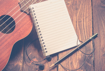 Ukulele guitar notebook and pencil on wood