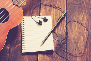 Ukulele guitar notebook and pencil on wood