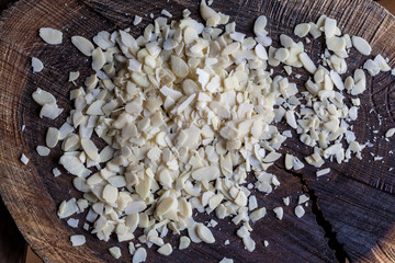 Flaked almonds heap on rough wooden cutting board directly from above