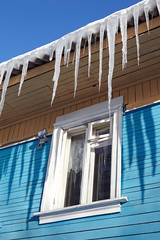 Dangerous icicles hanging from the roof of a wooden house