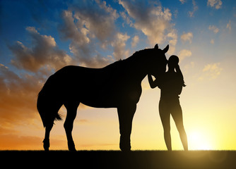 Naklejka premium Girl with a horse at sunset.