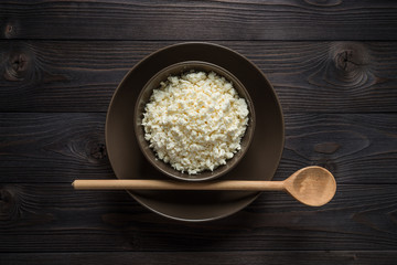 cottage cheese in a brown bowl on a dark wooden background