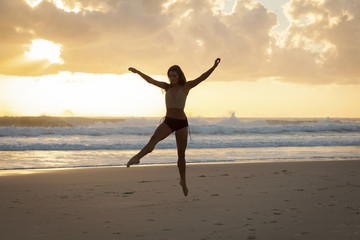 Fototapeta na wymiar Ballet dancer on beach at sunrise.