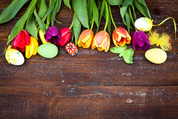 Easter eggs and fresh spring tulips on weathered wooden backgrou