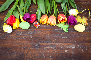 Easter eggs and fresh spring tulips on weathered wooden backgrou