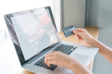 Hands holding a credit card and using laptop computer for online