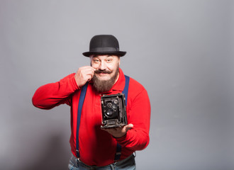 An elderly man in a bowler hat with an old camera