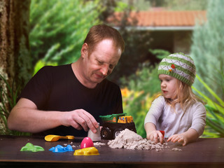 Little daughter and dad playing in the sand at the cottage. Heat, summer, sandpit. Molds for sand...
