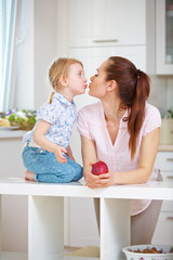 Obraz na płótnie Canvas Mutter und Tochter küssen sich in der Küche