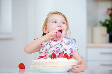 Kind leckt Sahne vom Finger beim Kuchen essen