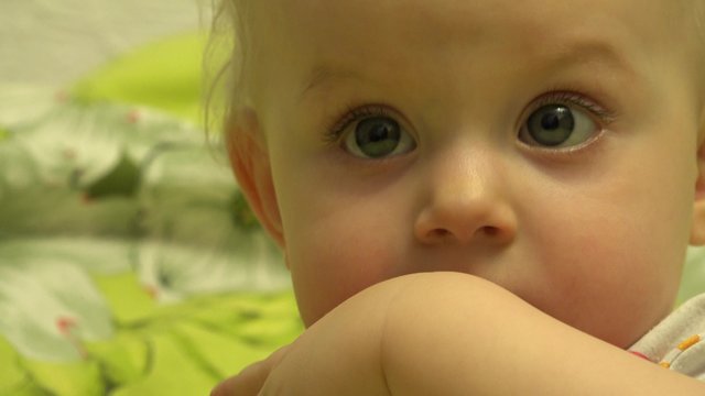 Surprised Baby Chews and Bites She's Fingers. Closeup. 4K UltraHD video.