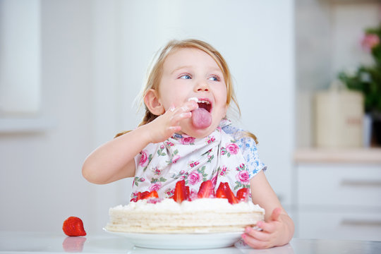 Kind leckt Sahne vom Finger beim Kuchen essen