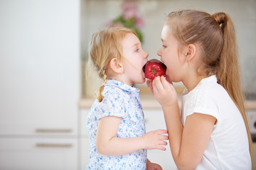 Zwei Kinder essen gemeinsam einen roten Apfel