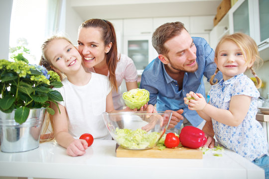 Glückliche Familie mit Salat in der Küche