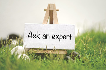 image concept white frame canvas on wooden tripod with word ASK AN EXPERT.Blurred and soft focus...