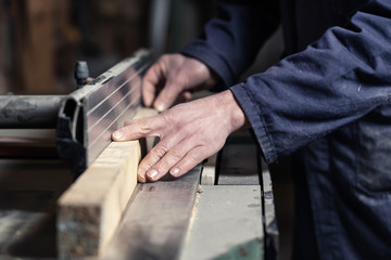 Carpenter's hands cutting wood with tablesaw