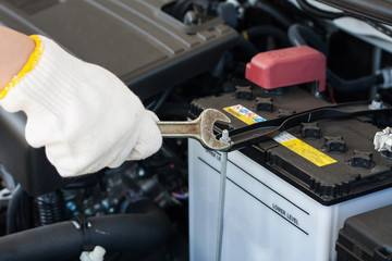 Hand with wrench repairing car engine