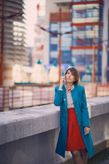 Business woman portrait outdoors talking at the phone with modern building as background.