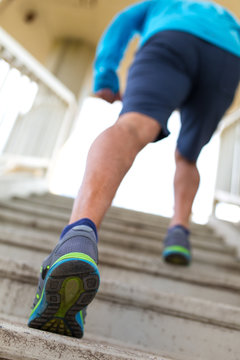 Man in blue shirt running up the stairs. Cross fit training.City environment.