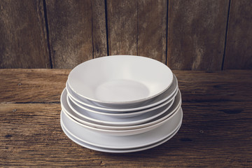 Multiple white dish, plate on grunge wooden table