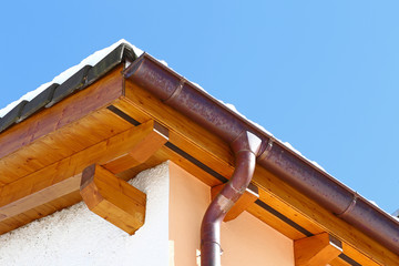 New roof top detail with ceramic tiles and copper water gutter with snow against blue skies
