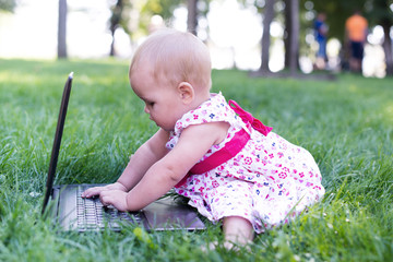 Little girl sitting on grass and playing tablet pc, toning photo