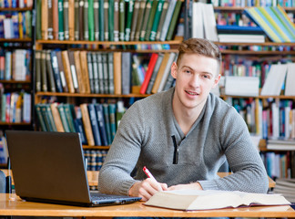 Male student with laptop studying in the university library