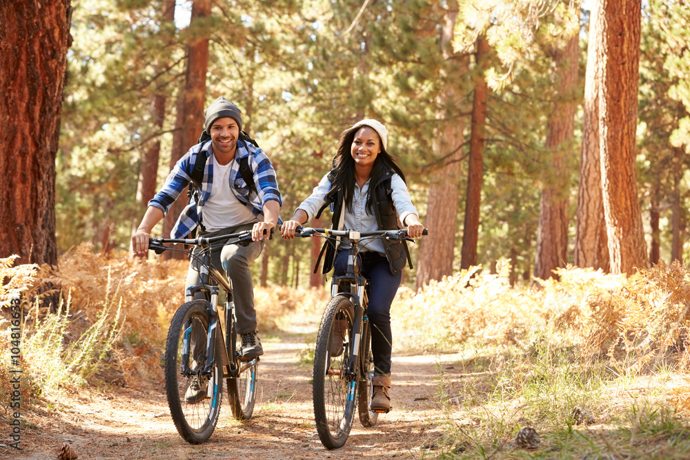 Wall mural african american couple cycling through fall woodland