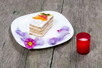 the burning candle and the plate with cake decorated with flower
