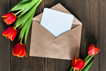 red tulips and kraft envelope on a wooden background