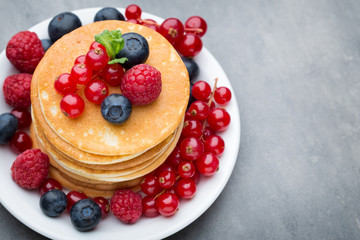 Stack of pancakes with blueberry and fresh berry.