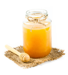 Glass can full of honey and wooden stick on a white background.