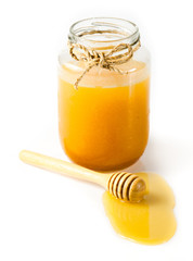 Glass can full of honey and wooden stick on a white background.