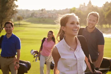 Foto auf Acrylglas Golf Gruppe von Golfern, die mit Golftaschen auf dem Fairway spazieren gehen
