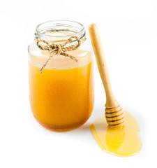 Glass can full of honey and wooden stick on a white background.