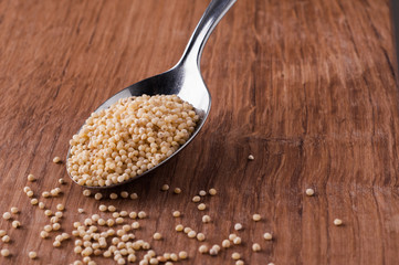 millet on metal spoon on brown wooden table