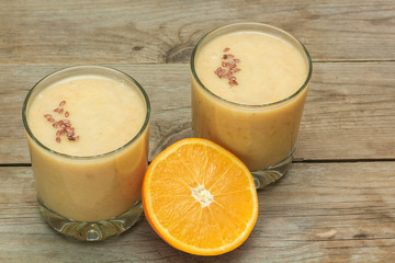 Obraz na płótnie Canvas couple of glasses of fruit smoothies and sliced orange