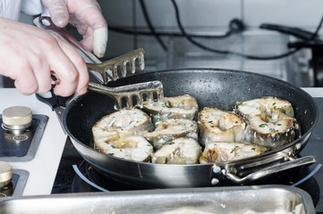 On a black skillet cooked pieces of fish, sturgeon.