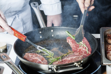 Cooking meat, frying steak in a frying pan, meat, rosemary oil.