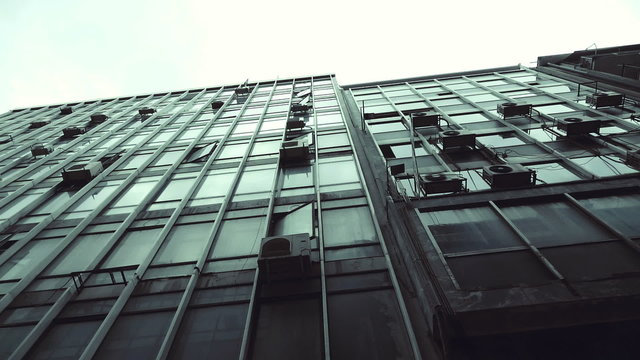 Passing by old abandoned urban building scyscraper offices tracking shot.Gimbal stabilized